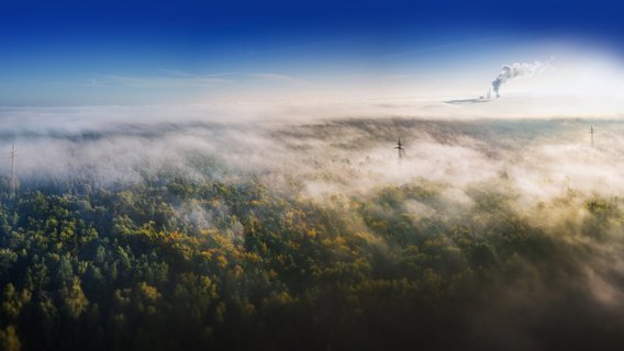 20250724_TNG_AdobeStock_459650306 weite Landschaft, die von einem dichten Nebel oder Dunst bedeckt ist.