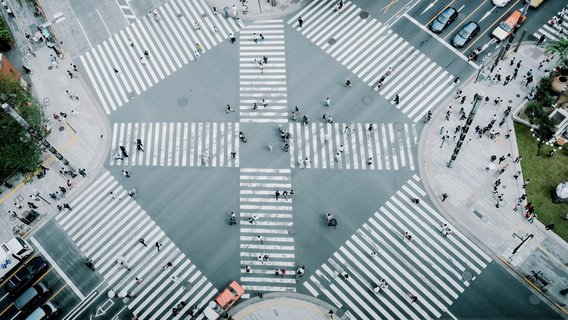 20250707_TNG_eyeem_100109965 Luftaufnahme einer belebten Fußgänger-Kreuzung mit Zebrastreifen in alle Richtungen in einer Großstadt.
